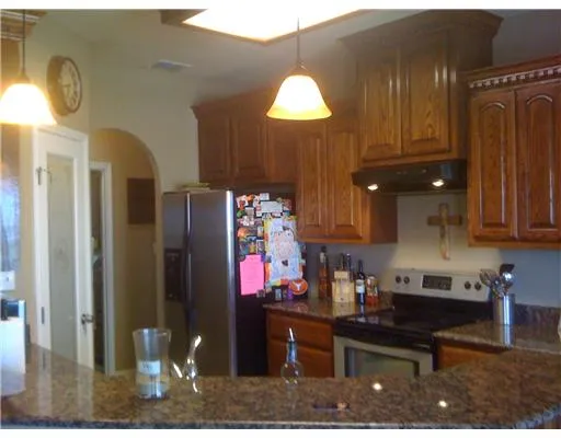 a kitchen with granite countertop a refrigerator dining table and chairs