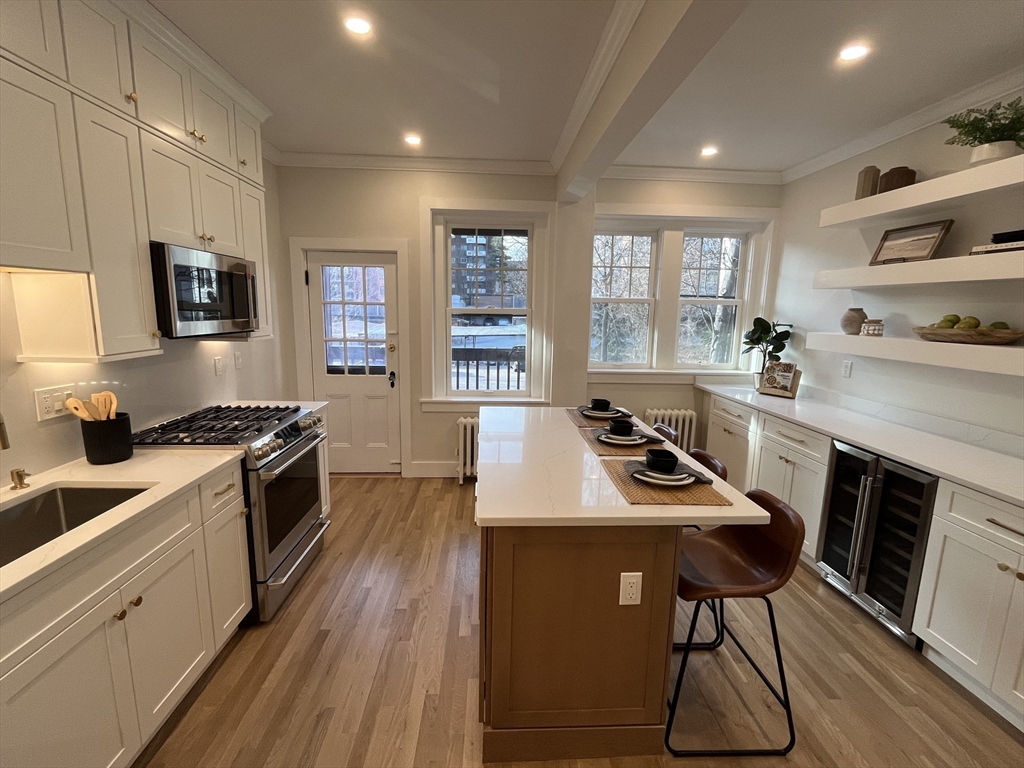 108 St Paul Street, Unit 2 Brookline, MA 02446 - Photo 3 of 15 a kitchen with stainless steel appliances granite countertop a stove top oven a sink dishwasher a dining table and chairs with wooden floor