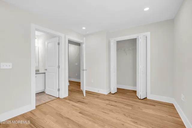 a view of an empty room with wooden floor and closet