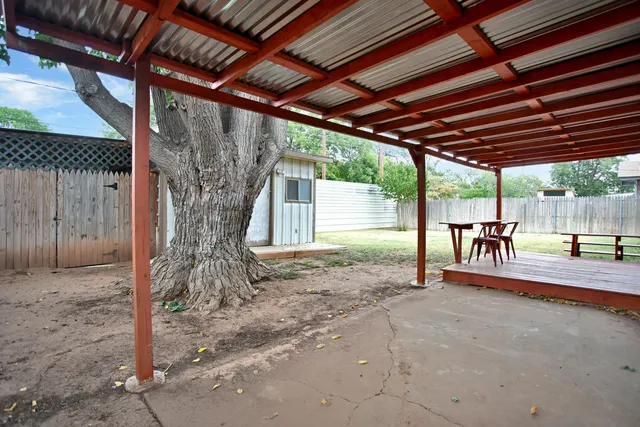 a view of a backyard with large trees and wooden fence