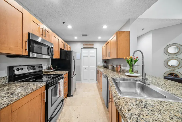 a kitchen with stainless steel appliances granite countertop a sink stove microwave and refrigerator