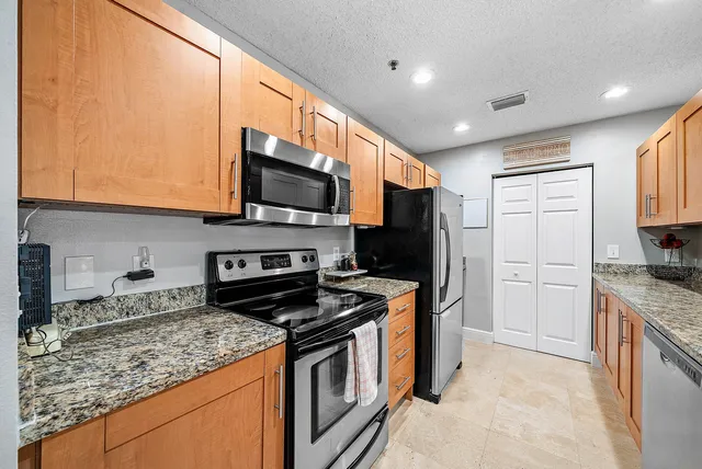 a kitchen with stainless steel appliances granite countertop a stove a sink and a microwave