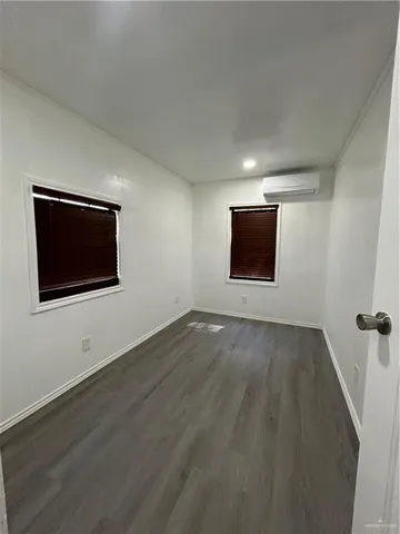 a view of an empty room with wooden floor and windows