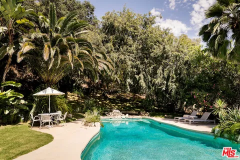 a view of backyard with a table and chairs under an umbrella