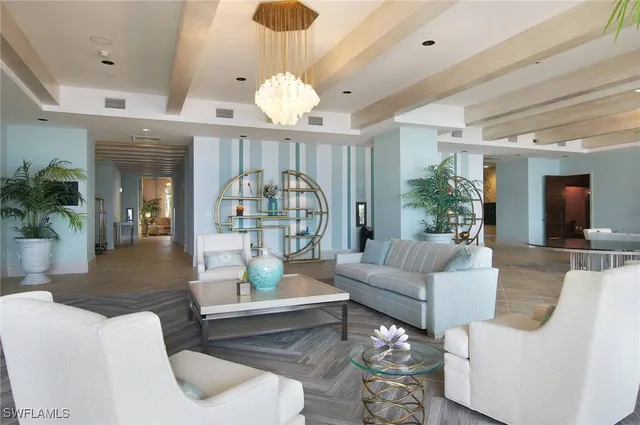 a living room with couches a dining table and a chandelier with wooden floor