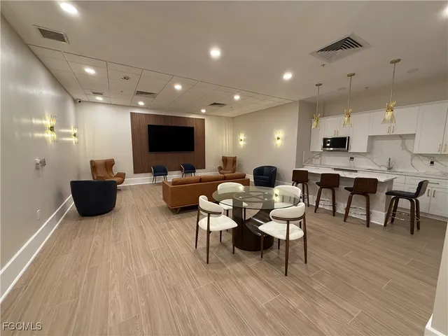 a living room with stainless steel appliances kitchen island granite countertop a dining table chairs and a refrigerator