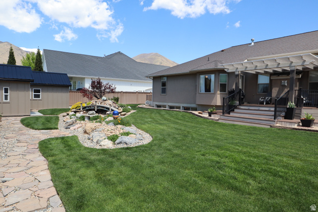 1055 North 1000 East Mapleton, UT 84664 - Photo 83 of 112 Expansive backyard featuring a lush lawn, flagstone pathway, and a decorative rock garden with a small bridge feature