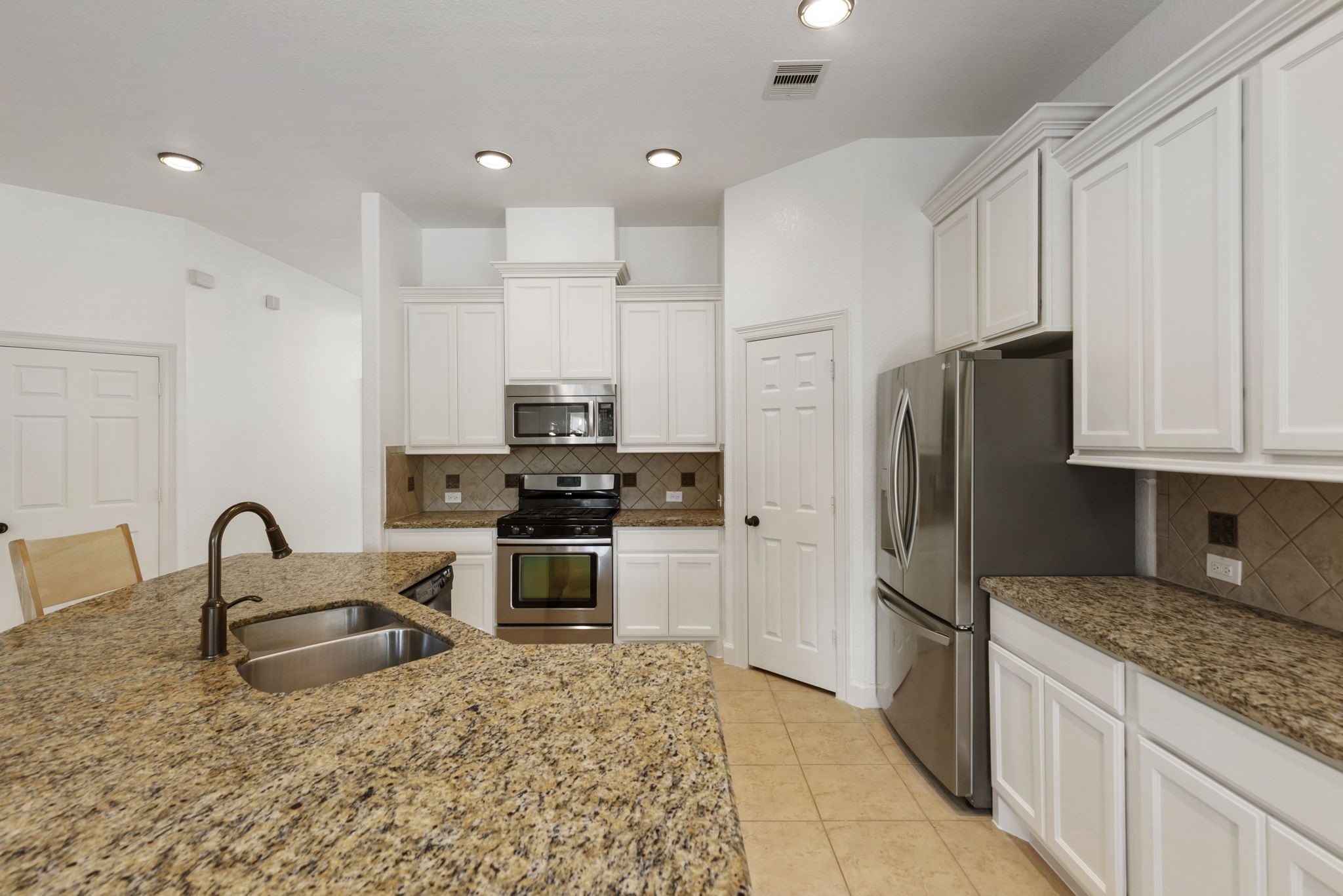 71 Sagamore Ridge Place The Woodlands, TX 77389 - Photo 11 of 34 a kitchen with granite countertop a refrigerator and a stove top oven
