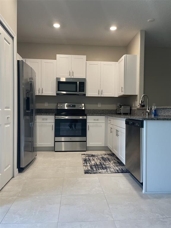 11901 Castine Street New Port Richey, FL 34654 - Photo 7 of 27 a kitchen with stainless steel appliances a stove a sink a microwave a refrigerator and cabinets