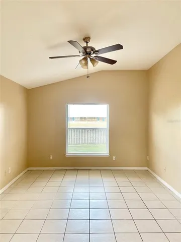 a view of an empty room and window and chandelier fan