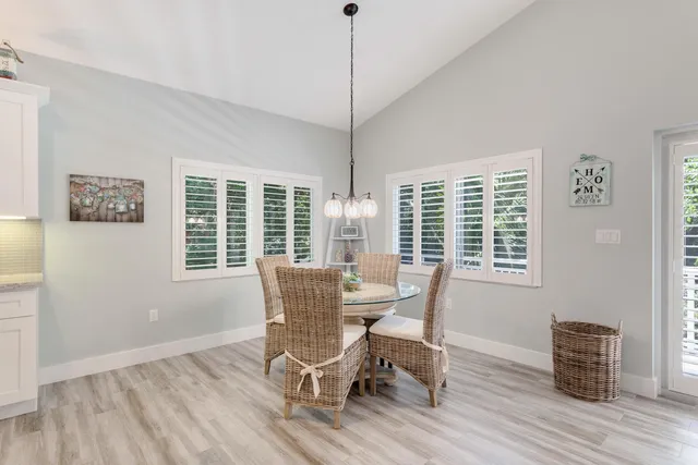 a dining room with wooden floor a chandelier a glass table and chairs