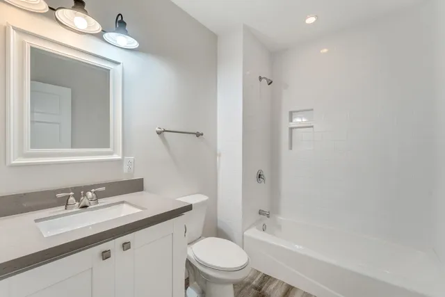 a bathroom with a granite countertop sink a toilet and shower