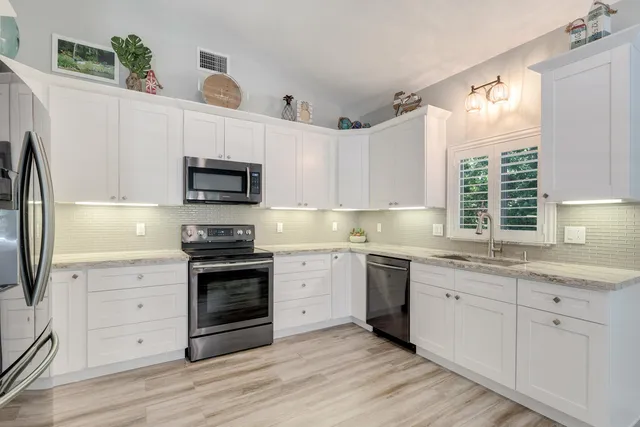 a kitchen with granite countertop white cabinets and stainless steel appliances