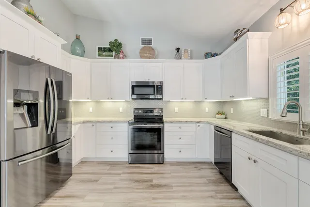 a kitchen with a sink stainless steel appliances and white cabinets