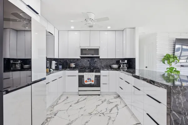 a kitchen with granite countertop a stove a sink and a microwave