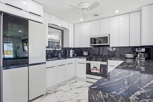 a kitchen with stainless steel appliances granite countertop a stove a sink and a microwave