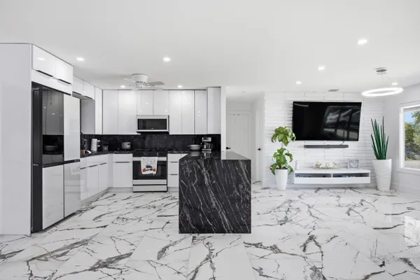 a large kitchen with stainless steel appliances kitchen island granite countertop a refrigerator and a stove top oven