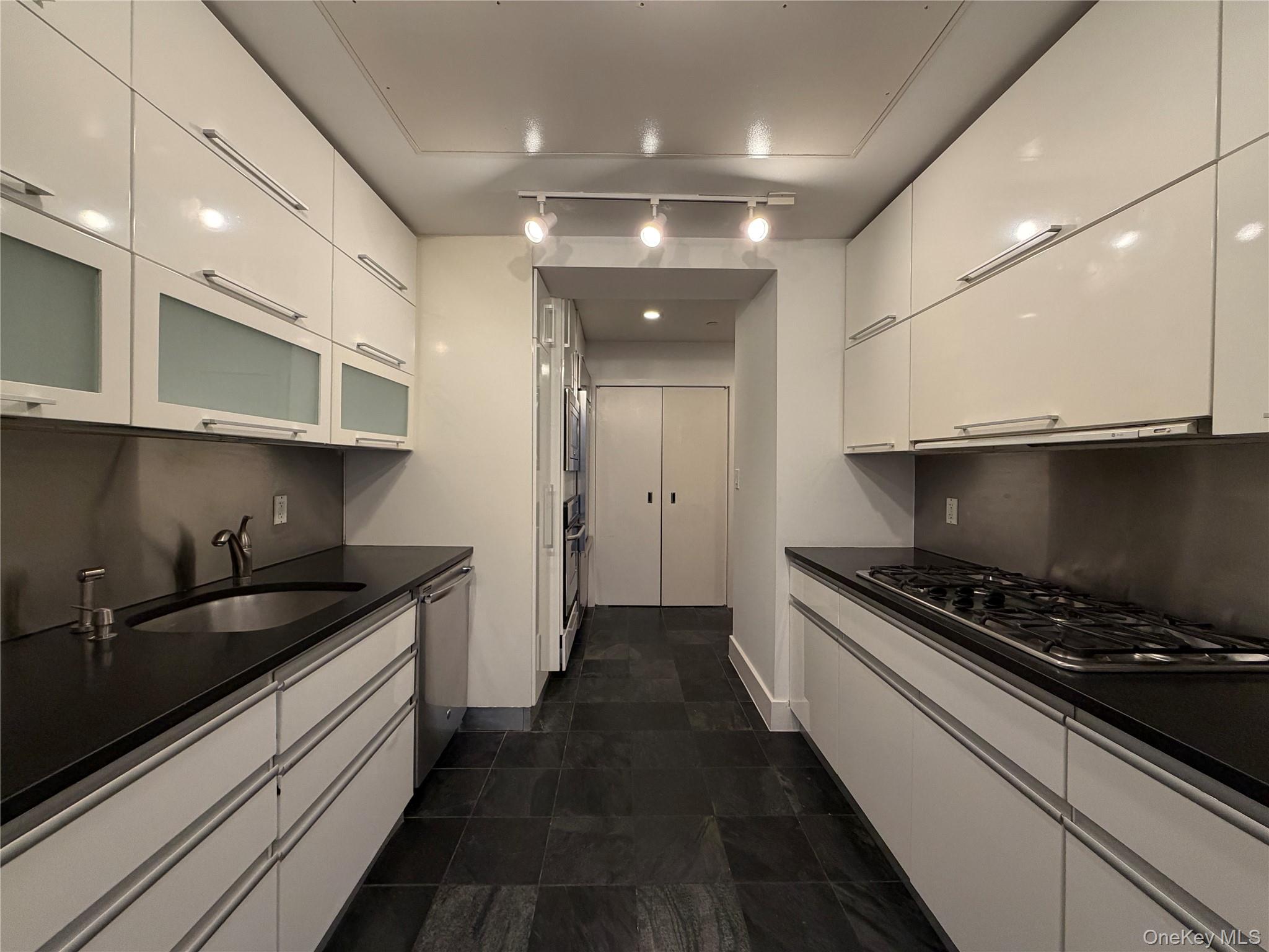 116 West 22nd Street, Unit 3 Manhattan, NY 10011 - Photo 4 of 11 Kitchen with white cabinetry, stainless steel appliances, glass insert cabinets, and modern cabinets