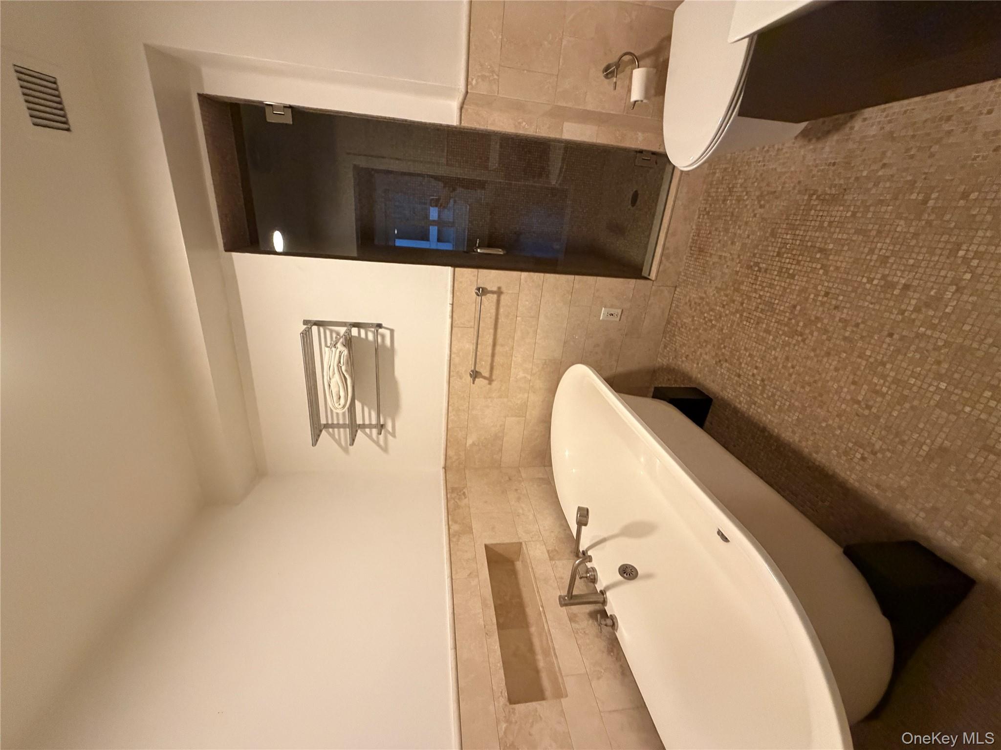 116 West 22nd Street, Unit 3 Manhattan, NY 10011 - Photo 9 of 11 Full bathroom featuring a wainscoted wall, tile walls, a soaking tub, a stall shower, and tile patterned flooring