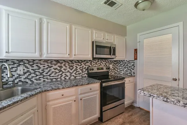 a kitchen with granite countertop white cabinets stainless steel appliances and a sink