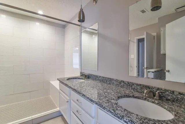 a bathroom with a granite countertop sink mirror and shower