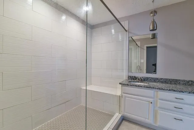a bathroom with a granite countertop sink a mirror and a shower