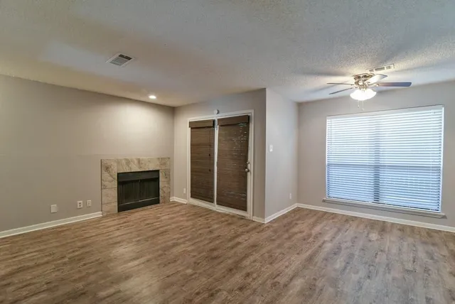 an empty room with windows fireplace and fan