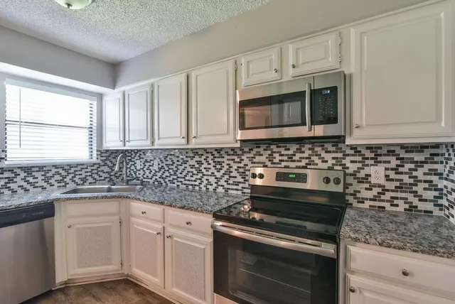 a kitchen with white cabinets appliances and a sink