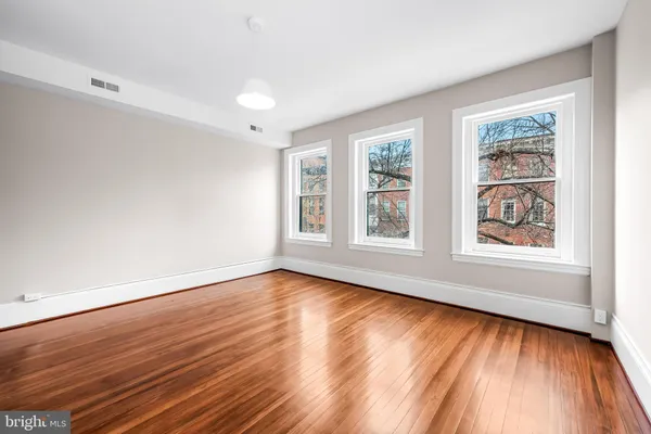 a view of an empty room with wooden floor and a window
