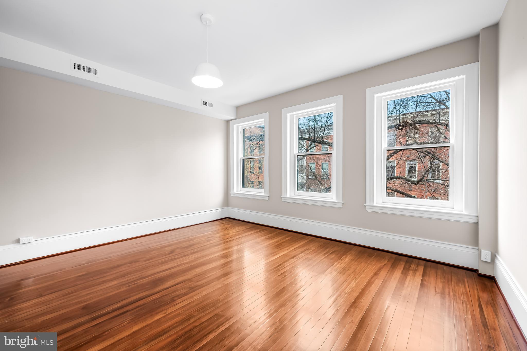 1202 Bolton Street, Unit 2 Baltimore, MD 21217 - Photo 11 of 25 a view of an empty room with wooden floor and a window