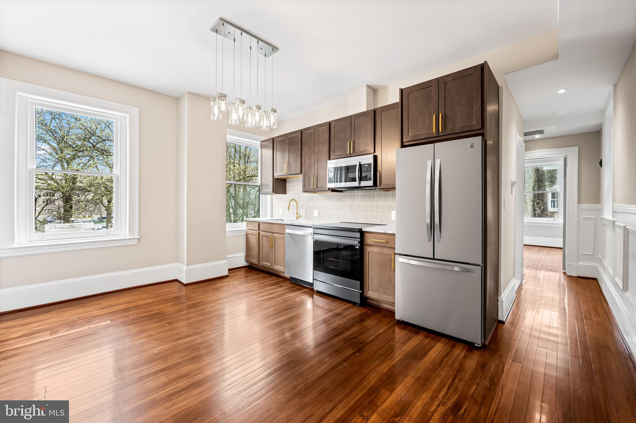 1202 Bolton Street, Unit 2 Baltimore, MD 21217 - Photo 6 of 25 a kitchen with kitchen island wooden floors white stainless steel appliances a sink and a window