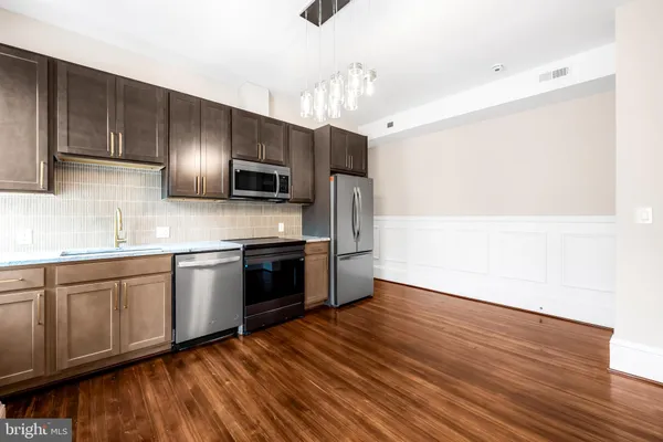 a kitchen with granite countertop wooden floors stainless steel appliances and sink