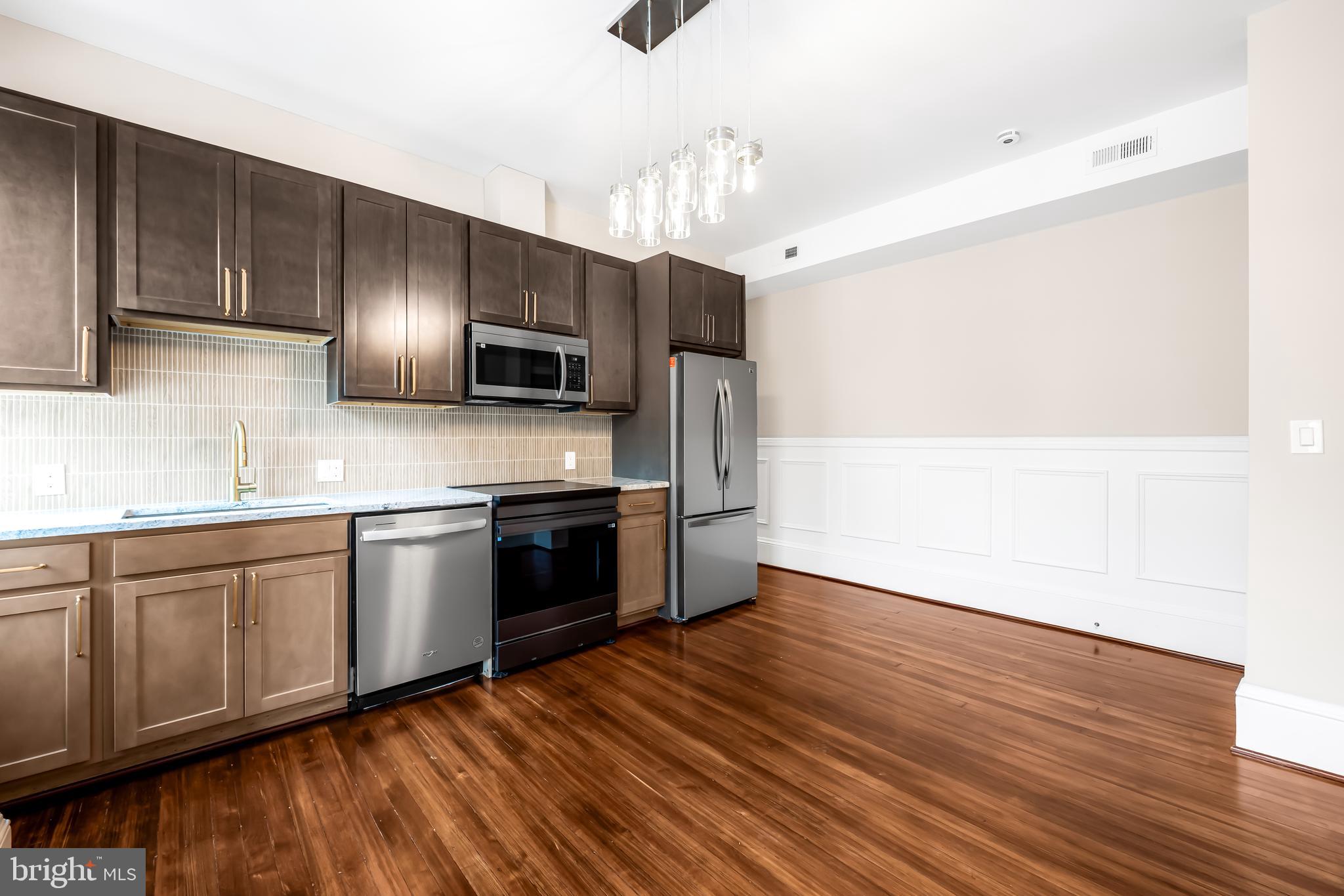 1202 Bolton Street, Unit 2 Baltimore, MD 21217 - Photo 7 of 25 a kitchen with granite countertop wooden floors stainless steel appliances and sink