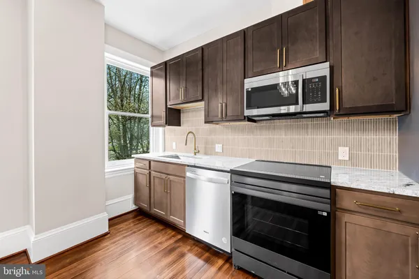 a kitchen with stainless steel appliances a stove microwave and sink