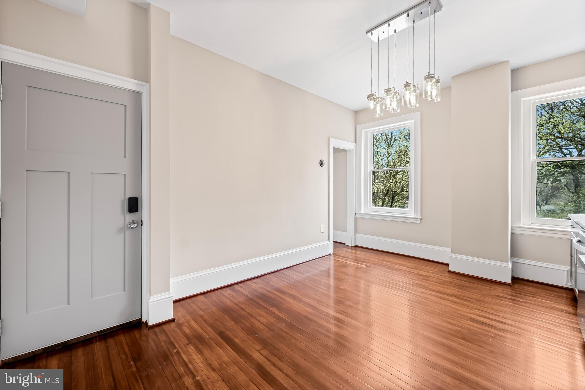 1202 Bolton Street, Unit 2 Baltimore, MD 21217 - Photo 9 of 25 an empty room with wooden floor chandelier and windows