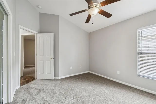 an empty room with chandelier fan and windows