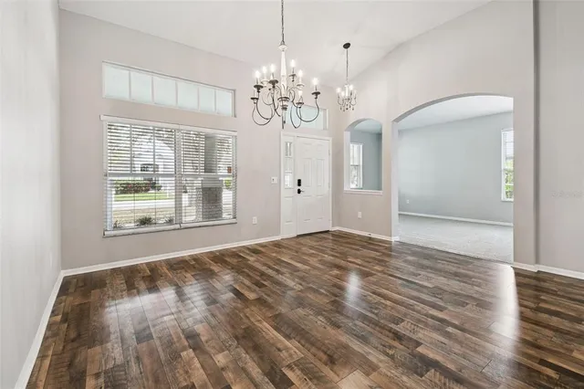 a view of an empty room with wooden floor and fan