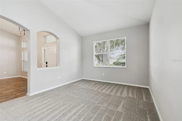 a view of an empty room with window and wooden floor