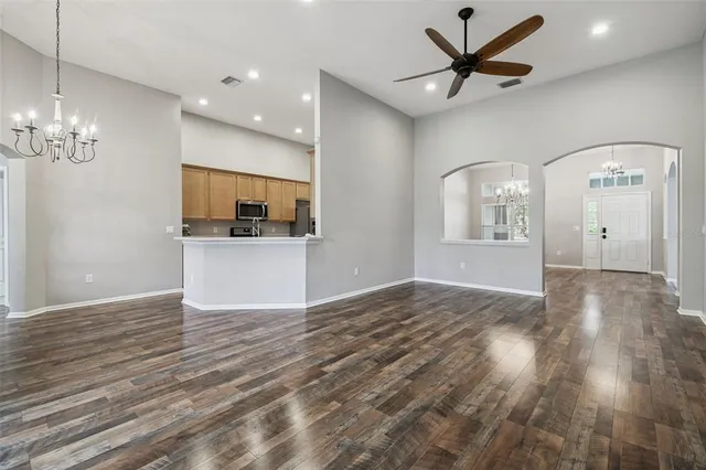 a view of a livingroom with a kitchen stove wooden floor and a ceiling fan