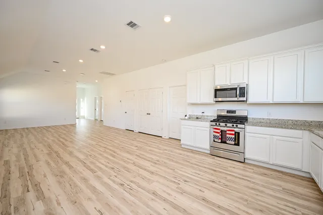 a kitchen with stainless steel appliances granite countertop a stove a sink and a microwave