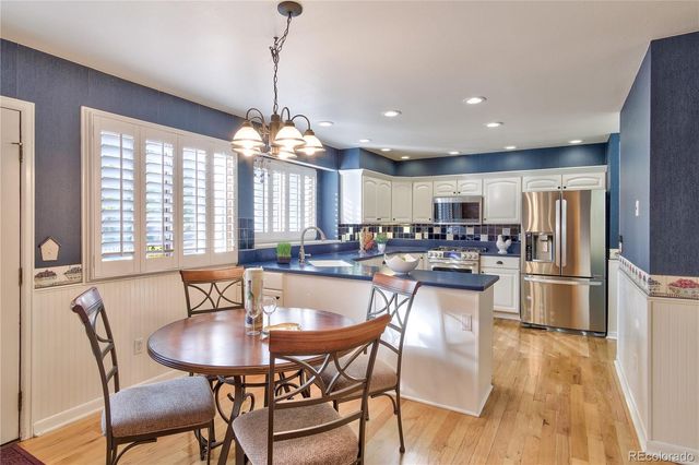 a kitchen with a dining table chairs and refrigerator