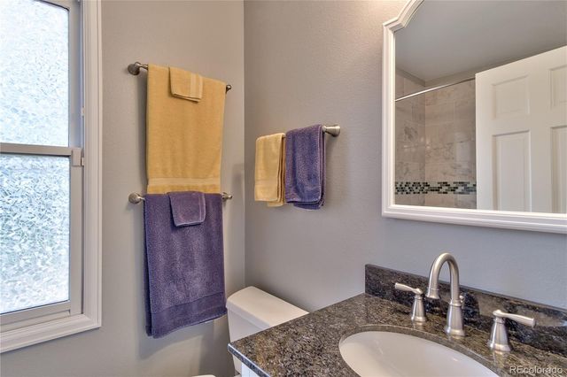 a bathroom with a granite countertop sink a toilet and a mirror