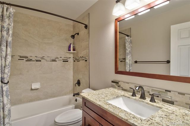 a bathroom with a granite countertop sink toilet and shower