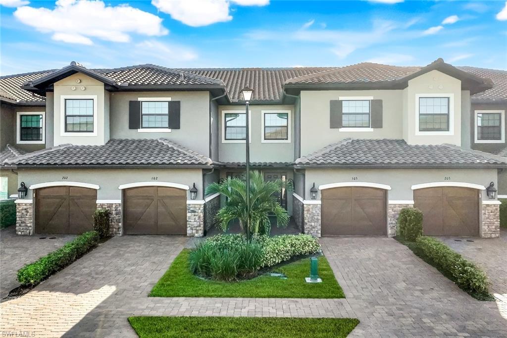 9641 Montelanico Loop, Unit 103 Naples, FL 34119 - Photo 23 of 28 a front view of a house with a yard and garage