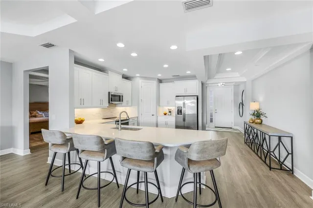 a kitchen with stainless steel appliances kitchen island granite countertop a dining table chairs refrigerator and microwave