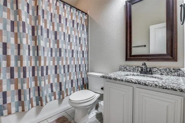 a bathroom with a granite countertop sink and a toilet
