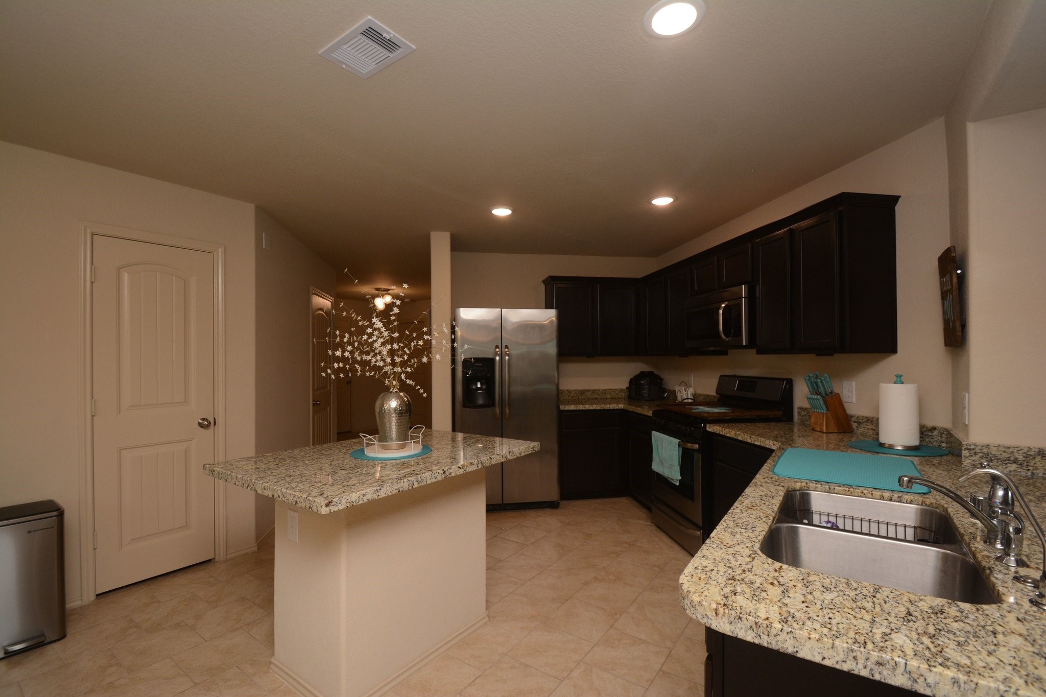 23318 Dukes Run Drive Spring, TX 77373 - Photo 10 of 41 This kitchen features dark wood cabinets, granite countertops, and stainless steel appliances. It includes a central island, a double sink, and recessed lighting, creating a modern and functional space.