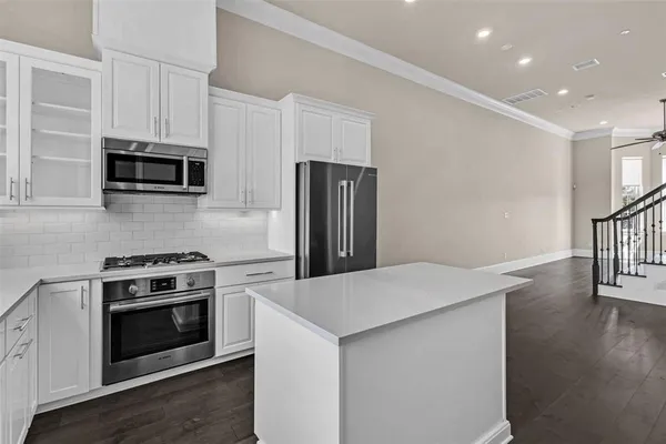 a kitchen with granite countertop a stove a microwave a refrigerator a sink and dishwasher with wooden floor