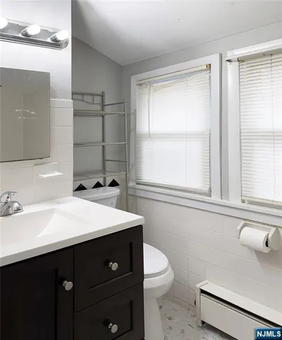 a bathroom with a sink vanity granite toilet and a mirror
