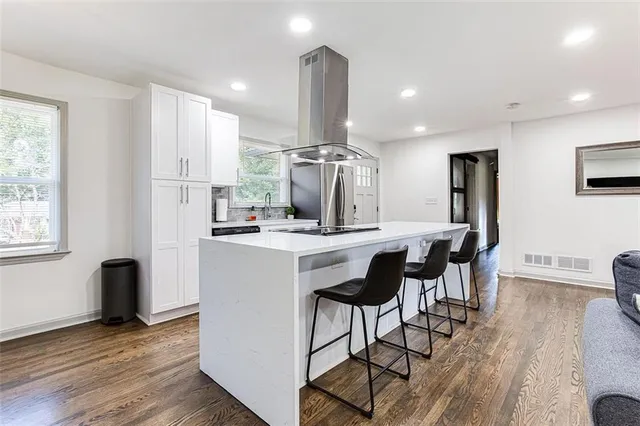 a kitchen with stainless steel appliances kitchen island granite countertop a dining table chairs and granite counter tops